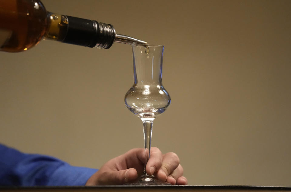 A barman pours the plum brandy into a glass in the bar in Belgrade, Serbia, Friday, Nov. 11, 2022. The U.N.'s culture and education organization is set later this month to review Serbia's bid to include "social practices and knowledge related to the preparation and use of the traditional plum spirit - sljivovica" on the list of world intangible cultural heritage. (AP Photo/Darko Vojinovic)