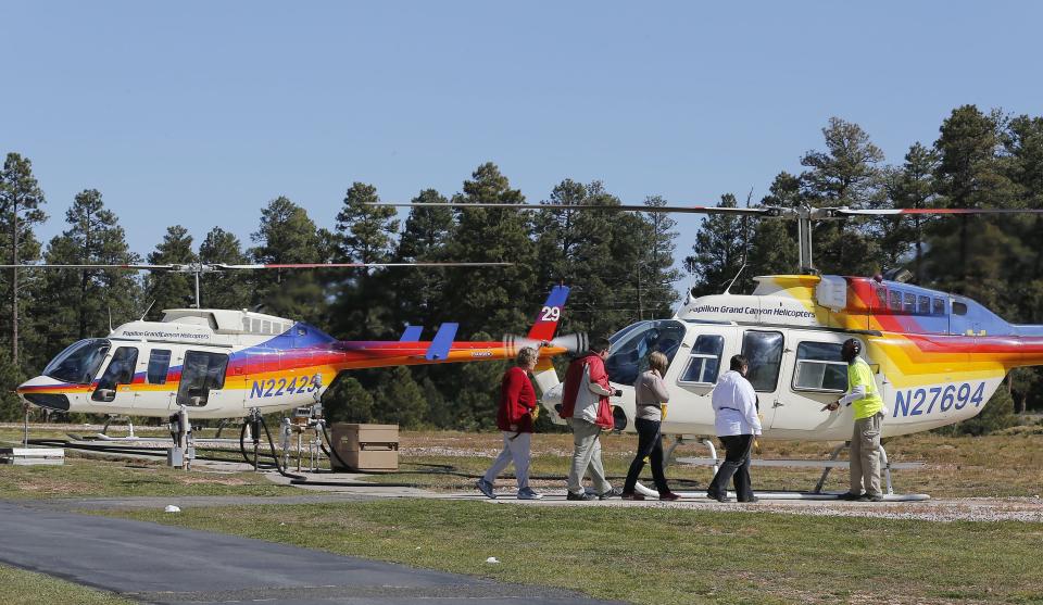 In this Oct. 11, 2013 photo, tourists prepare to get on a helicopter prior to taking a tour of the Grand Canyon, at Grand Canyon National Park Airport in Tusayan, Ariz. Air tour operators that use aircraft with quiet technology will be able to fly more people over the Grand Canyon. The Federal Aviation Administration said it plans to release 1,721 flight allocations this year that had been abandoned to those commercial tour operators, as long as their active fleet doesn't increase noise in the park overall. (AP Photo/Ross D. Franklin)