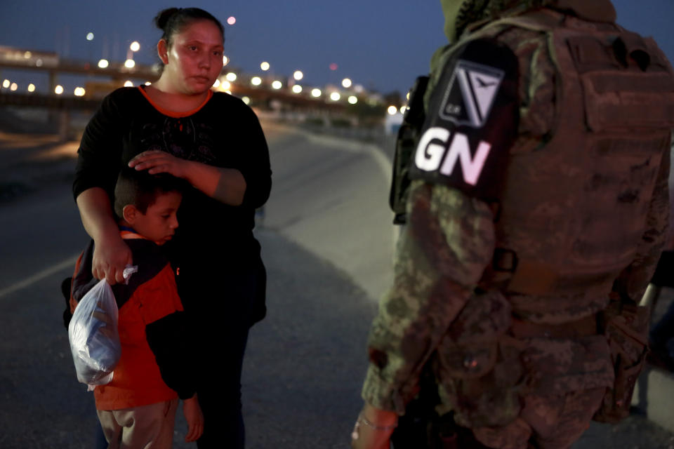 FILE - In this June 24, 2019 file photo, a military police officer wearing the insignia of Mexico's new National Guard detains Guatemalan migrants to keep them from crossing from Ciudad Juarez, Mexico to El Paso, Texas. Under pressure from the U.S. government, Mexico’s immigration policy has moved from promising to help migrants, to one characterized by militarized enforcement under the growing influence of the country’s Foreign Secretary Marcelo Ebrard. (AP Photo/Christian Chavez, File)