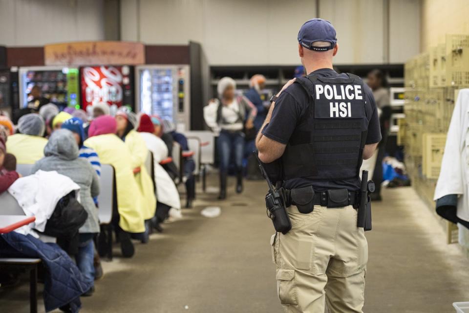 This image released by Immigration and Customs Enforcement (ICE) shows a Homeland Security Investigations (HSI) officer guarding suspected undocumented workers on August 7, 2019.