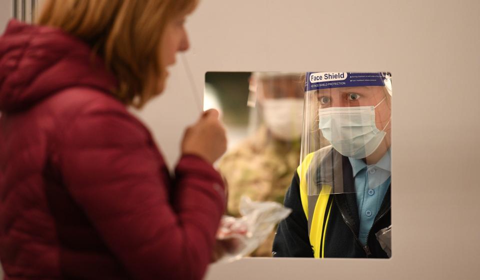 A member of the public uses a swab before passing it to a waiting member of Test and Trace at the mass and rapid testing centre for the novel coronavirus COVID-19 at a Tennis centre in Liverpool on November 6, 2020. - To avoid extending the lockdown, Johnson is pinning his hopes on an ambitious new programme of Covid testing to detect and isolate infected people, starting with a city-wide trial launching in Liverpool today. (Photo by Oli SCARFF / AFP) (Photo by OLI SCARFF/AFP via Getty Images)