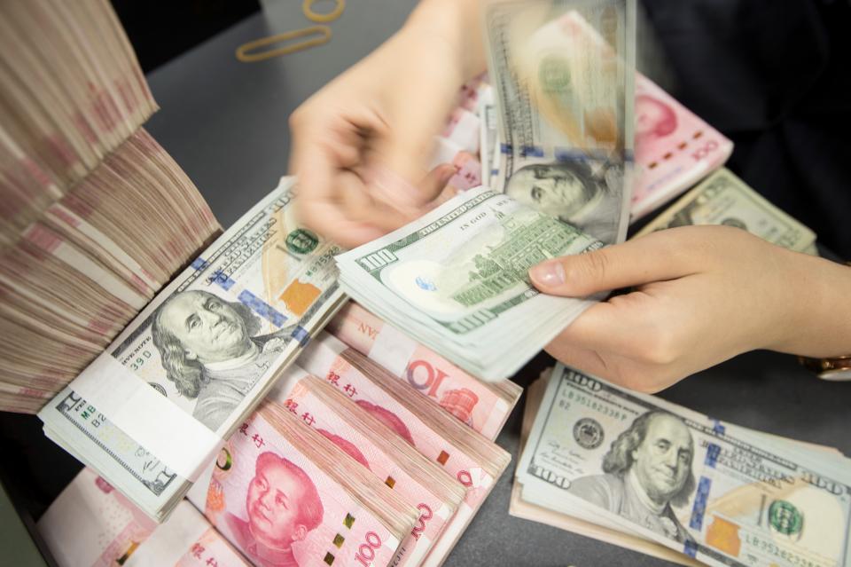 A Chinese bank employee counts 100-yuan notes and US dollar bills at a bank counter in Nantong in China's eastern Jiangsu province on August 6, 2019. - The Chinese currency steadied on August 6, a day after Beijing let the yuan weaken against the dollar, sending markets into freefall and leading the US to formally designate China a "currency manipulator". (Photo by STR / AFP) / China OUT        (Photo credit should read STR/AFP/Getty Images)