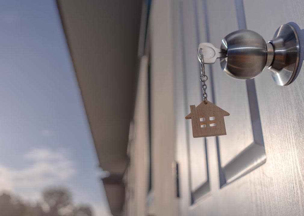 low angle shot of keychain with miniature house figurine hanging from door and the sky visible in the background