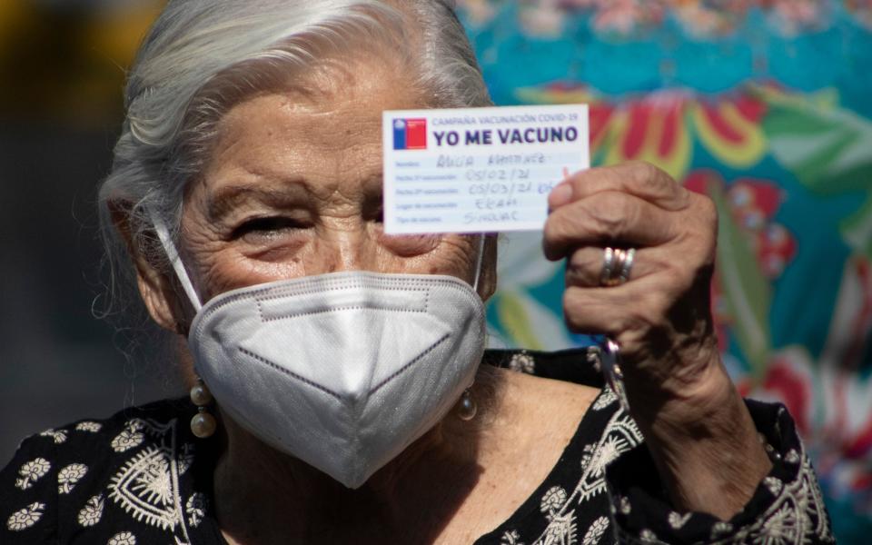 Alicia Martinez holds up her vaccination card after she was injected with a second dose of China's Sinovac COVID-19 vaccine  - Esteban Felix/AP Photo