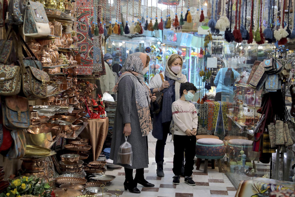 Mask-clad shoppers look at items in a shop ahead of the Persian New Year, or Nowruz, meaning "New Day." in northern Tajrish traditional bazaar, in Tehran, Iran, Wednesday, March 17, 2021. (AP Photo/Ebrahim Noroozi)