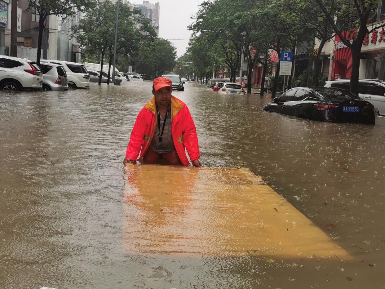 A sanitation worker cleans rubbish from a flooded street on Wednesday in Zhengzhou, Henan province  (Visual China Group/Getty)