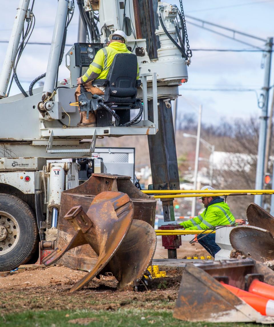 The LE Myers Co employees, working for Duke Energy, attach a drill head as they work on creating new foundations for electric poles along Patterson Drive on Tuesday, March 15, 2023. 