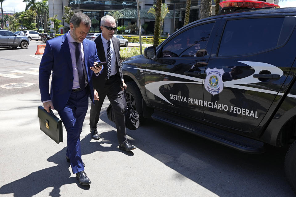 Lawyer Paulo Cunha, left, accompanied by adviser Osmar Crivelatti, arrives to return weapons received by Brazil's former President Jair Bolsonaro at the Federal Police headquarters in Brasilia, Brazil, Friday, March 24, 2023. Representatives of Bolsonaro on Friday returned weapons he received from the United Arab Emirates and a set of jewels from Saudi Arabia, both of which he received during his presidency, as he was ordered to do by a Brazilian government watchdog. (AP Photo/Eraldo Peres)