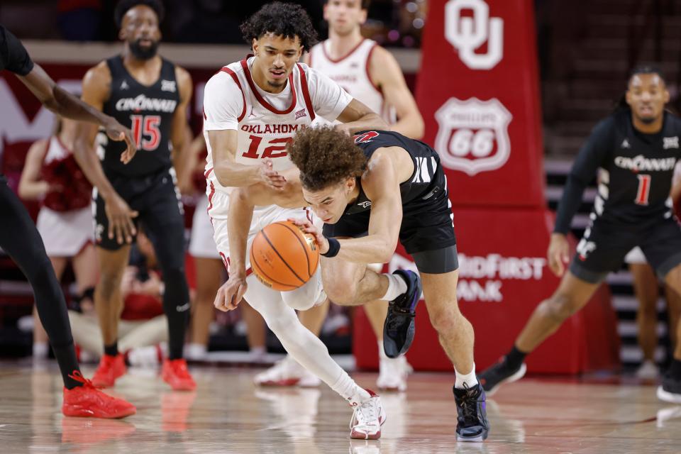 Oklahoma Sooners guard Milos Uzan (12) and Cincinnati Bearcats guard Dan Skillings Jr. (0) reach for a loose ball. Skilling returned to the lineup for the Bearcats after missing a game with a hip injury.