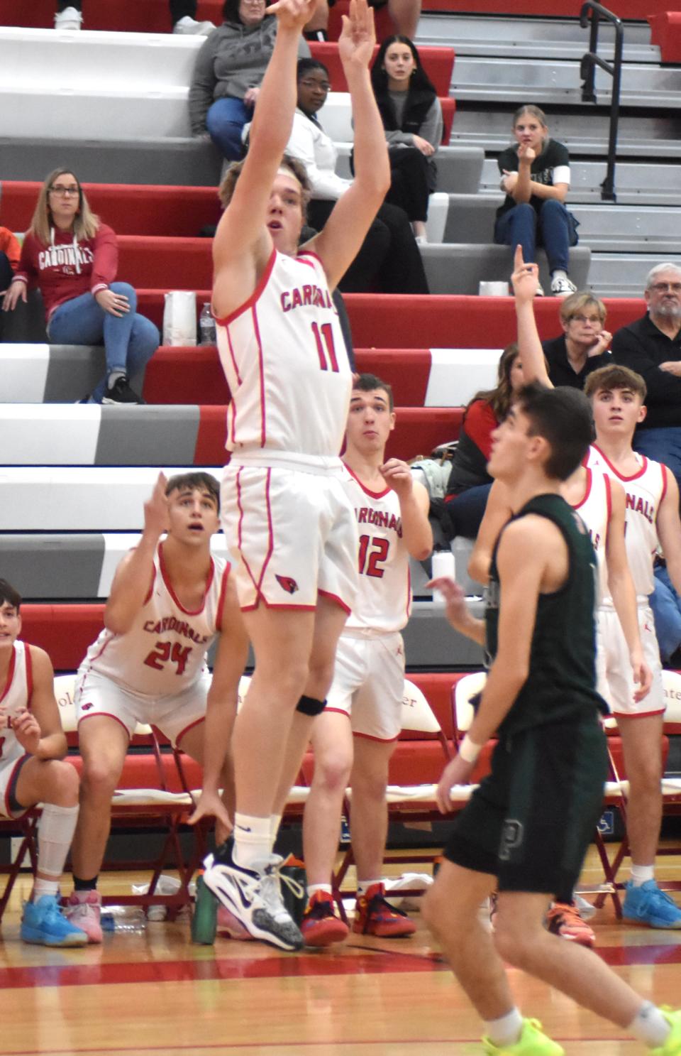 Coldwater's Steven Covell (11) fires away from three while his teammates cheer him on Friday night versus Pennfield.