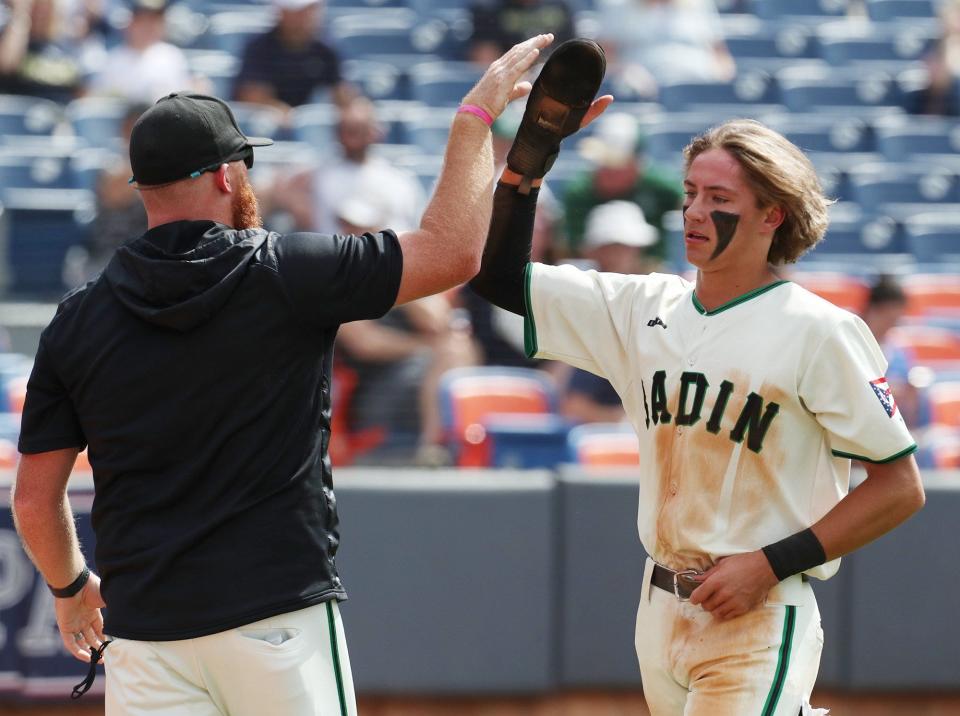 A Badin coach high-fives Landyn Vidourek after he scored against Archbishop Hoban in the first inning of the Division II state semifinal game at Canal Park in Akron on Friday, June 9, 2022.