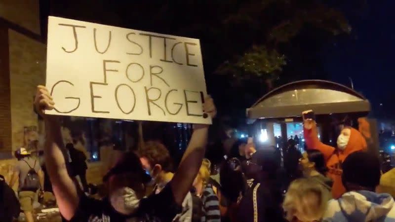 Protesters gather around an on fire entrance of a police station, in Minneapolis