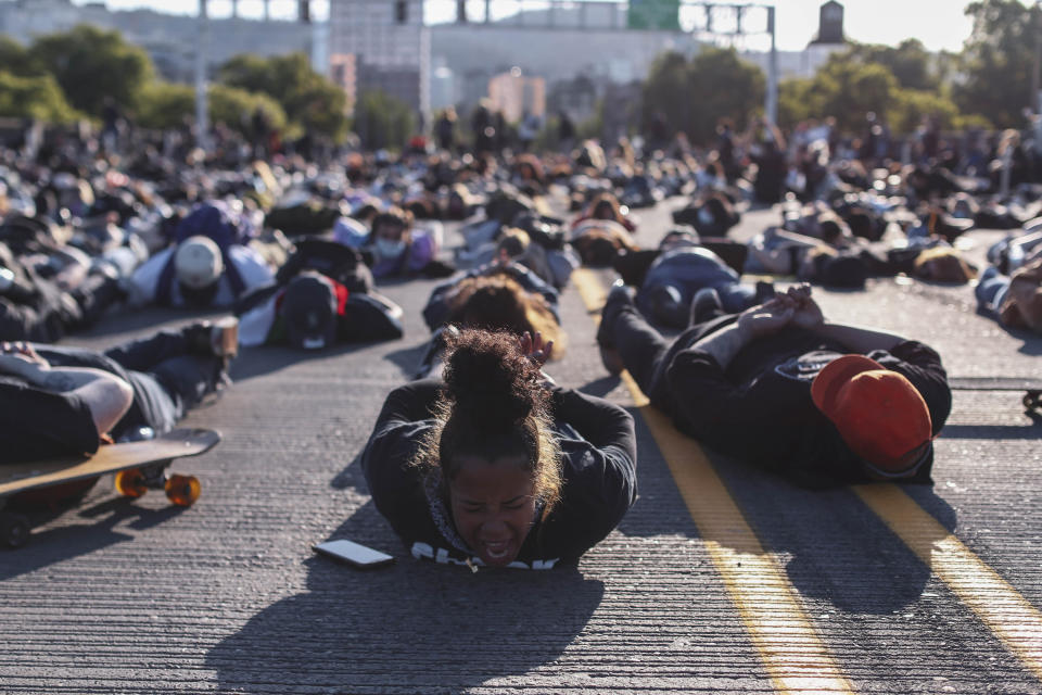 FILE - In this Monday, June 1, 2020, file photo, protesters prepare to observe nine minutes of silence on the Burnside Bridge in Portland, Ore. City commissioners in Portland voted, Wednesday, June 17, 2020 to cut nearly $16 million from the Portland Police Bureau's budget in response to concerns about police brutality and racial injustice. The cuts are part of a city budget approved by the commissioners by a 3-1 vote in a contentious meeting. (Beth Nakamura/The Oregonian via AP, File)