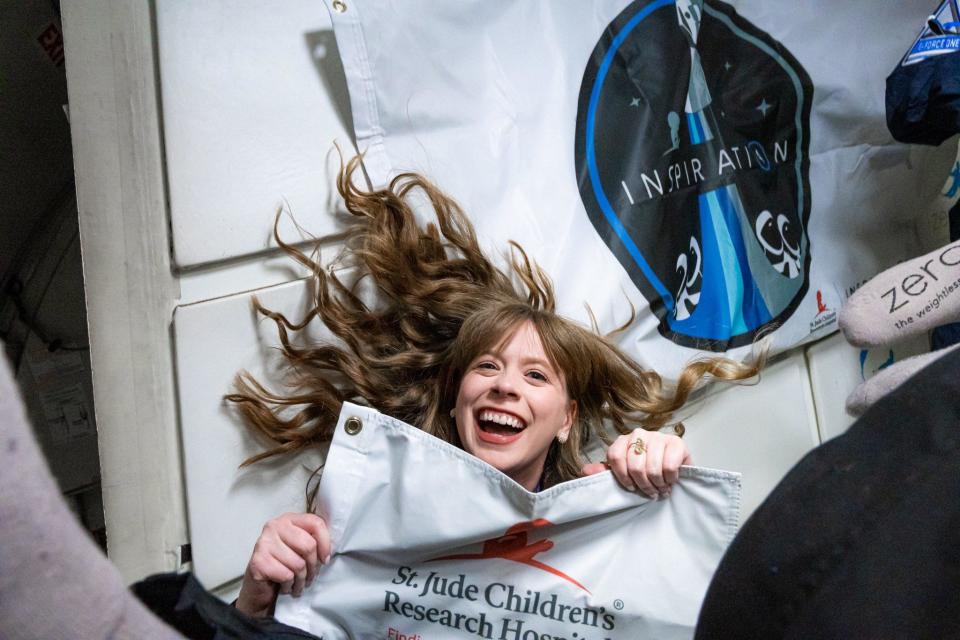 Treated for bone cancer at St. Jude Children's Research Hospital when she was 10, Hayley Arceneaux, now a physician assistant at the famed institution, waves the flag during a zero-gravity training flight. / Credit: Inspi4ration