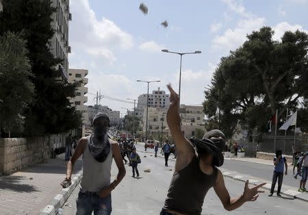 Masked Palestinian protesters throw stones at Israeli troops during clashes in the occupied West Bank city of Bethlehem, September 21, 2015. REUTERS/Ammar Awad