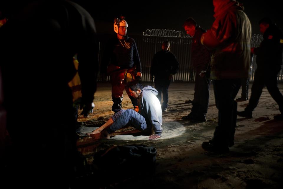 Authorities hold a Honduran migrant who was rescued as he tried to cross the U.S. border by the sea in Tijuana beach, Mexico, Thursday, Nov. 29, 2018. Aid workers and humanitarian organizations expressed concerns Thursday about the unsanitary conditions at the sports complex in Tijuana where more than 6,000 Central American migrants are packed into a space adequate for half that many people and where lice infestations and respiratory infections are rampant. (AP Photo/Ramon Espinosa)