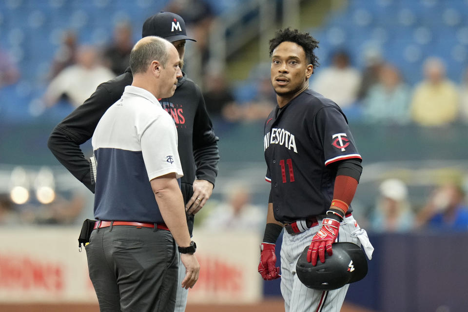 Minnesota Twins' Jorge Polanco (11) talks to manager Rocco Baldelli and a trainer after getting hurt running to first base during the first inning of a baseball game against the Tampa Bay Rays Thursday, June 8, 2023, in St. Petersburg, Fla. Polanco left the game. (AP Photo/Chris O'Meara)