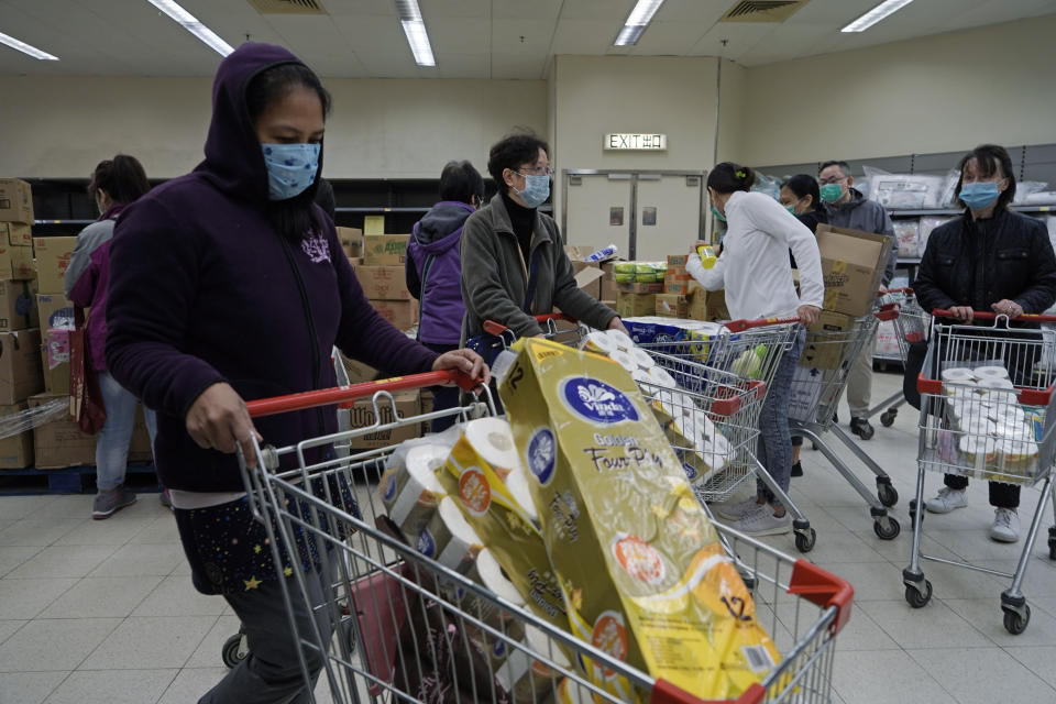 Customers wearing masks, purchase tissue papers in a supermarket in Hong Kong, Saturday, Feb. 8, 2020. Widespread panic-buying of essentials such as toilet rolls and rice has hit in Hong Kong, a knock-on effect of the virus outbreak in mainland China. (AP Photo/Kin Cheung)