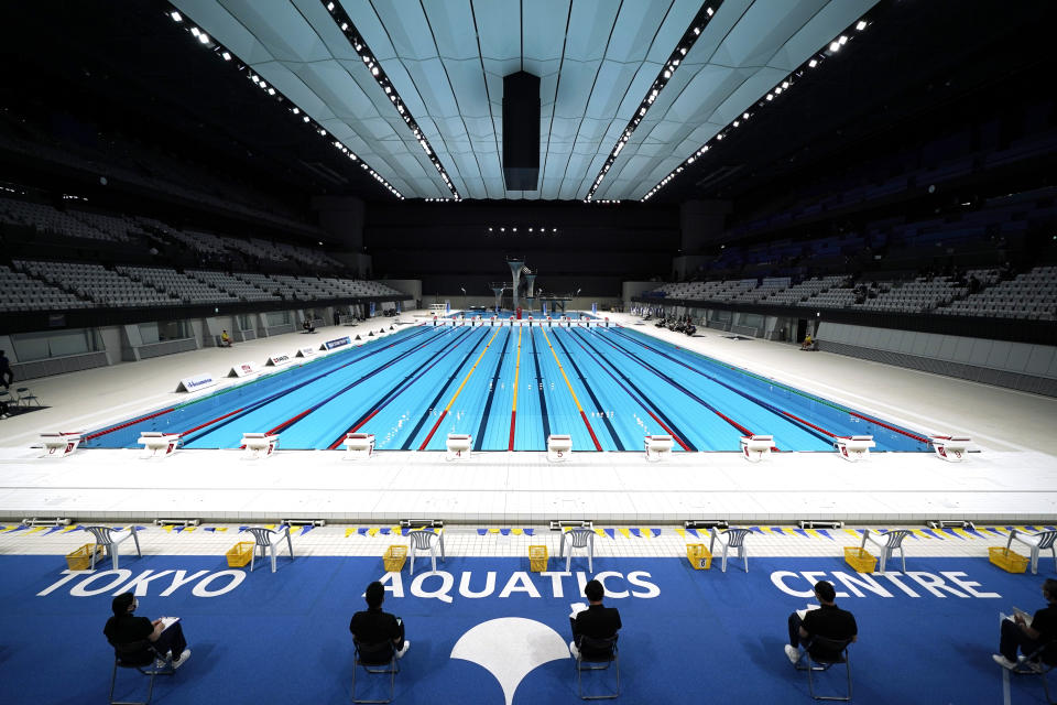 FILE - In this April 26, 2021, file photo, Tokyo 2020 Olympic Games Organizing staff prepare a Paralympic swimming test event at the Tokyo Aquatics Center, in Tokyo. The Tokyo Olympics are not looking like much fun: Not for athletes. Not for fans. And not for the Japanese public, who are caught between concerns about the coronavirus at a time when few are vaccinated on one side and politicians and the International Olympic Committee who are pressing ahead on the other. (AP Photo/Eugene Hoshiko, File)