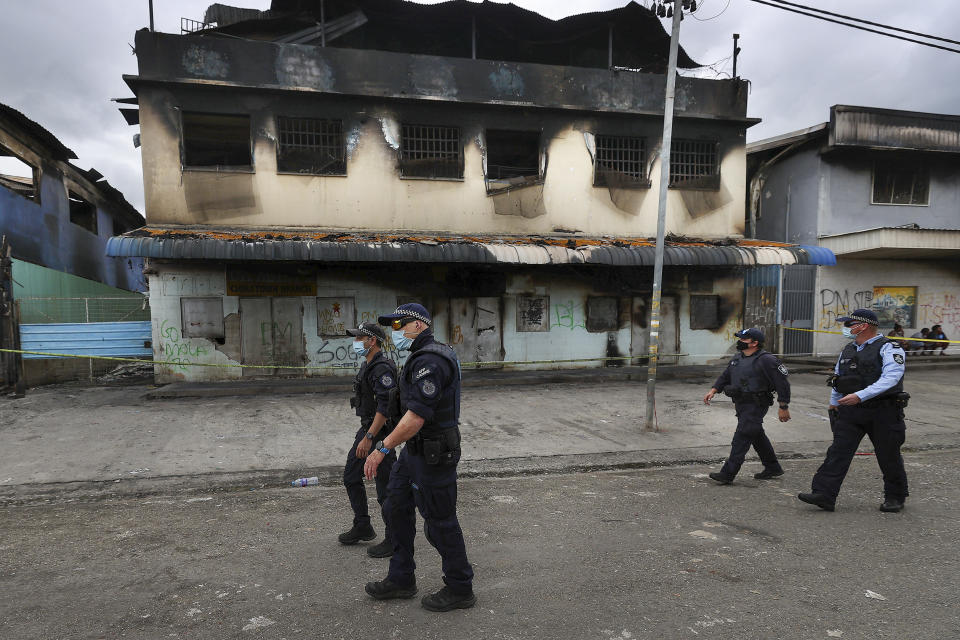 Australian Federal Police inspect burnt out areas of Chinatown in Honiara, Solomon Islands, Tuesday, Nov. 30, 2021. New Zealand announced Wednesday, Dec. 1, 2021, that they will send up to 65 military and police personnel to the Solomon Islands over the coming days after rioting and looting broke out there last week.(Gary Ramage via AP)