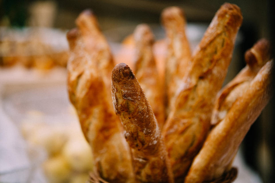 Close-up of several freshly baked baguettes standing upright in a basket