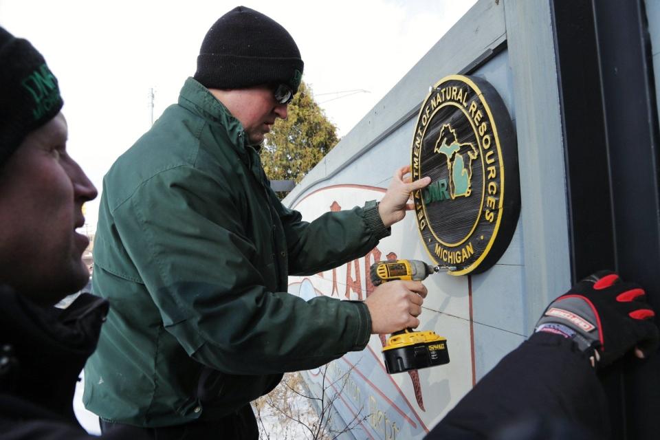 DNR Park rangers DJ Coffey, right, and Kale Leftwich add a DNR sign to the Belle Isle entrance sign on Monday, Feb. 10, 2014, during the first day the park in Detroit became a state park.