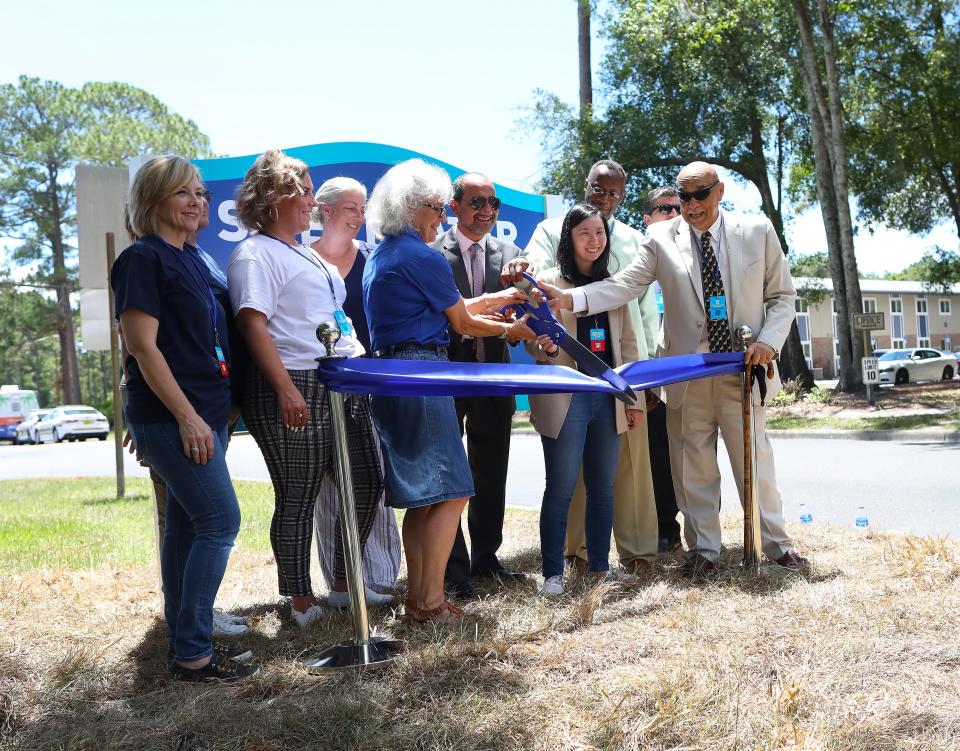 Officials cut a ribbon during a celebration for the re-opening of the newly renovated Sweetwater Square apartments in Gainesville.