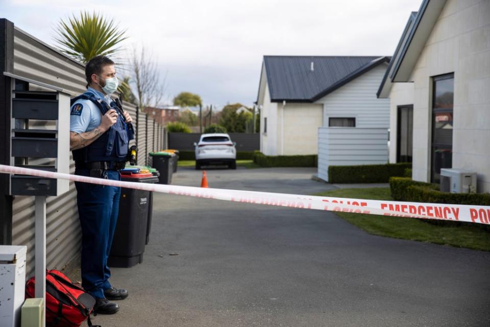 A police officer stands in the driveway of a house where three children were found dead (AP)