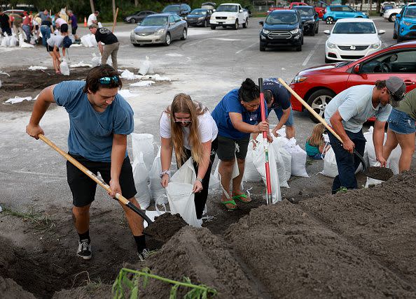 Chris Tate (left) and Heather Tallmadge and other people fill sandbags at Helen Howarth Park as they prepare for the possible arrival of Hurricane Ian on September 26, 2022, in St. Petersburg, Florida.