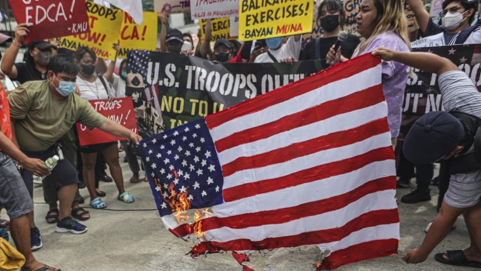 Demonstrators burn a U.S. flag during a rally in front of Camp Aguinaldo military headquarters in Quezon City, Philippines, on April 11, 2023, as they protest against opening ceremonies for the joint military exercise Balikatan, or Tagalog for shoulder-to-shoulder. The U.S. and the Philippines began their largest combat exercises in decades that will involve live-fire drills, including a boat-sinking rocket assault in waters across the South China Sea and the Taiwan Strait. (Gerard Carreon/AP)