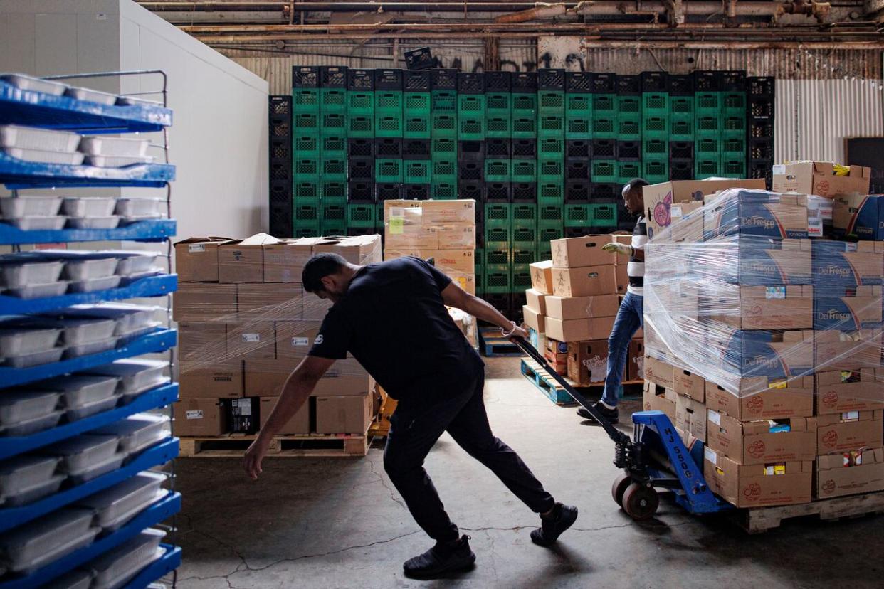 A volunteer at the Feed Scarborough Food Bank moves donation boxes through the charity's Toronto warehouse on Aug. 3, 2023. (Evan Mitsui/CBC - image credit)