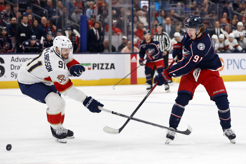 Columbus Blue Jackets forward Kent Johnson, right, passes the puck in front of Florida Panthers defenseman Oliver Ekman-Larsson during the second period of an NHL hockey game in Columbus, Ohio, Sunday, Dec. 10, 2023. (AP Photo/Paul Vernon)