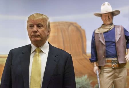U.S. Republican presidential candidate Donald Trump stands in front of a statue of actor John Wayne during a campaign event at the museum and birthplace of the actor while campaigning for the 2016 Republican presidential nomination in Winterset, Iowa in a June 27, 2015 file photo. REUTERS/Brian Frank/files