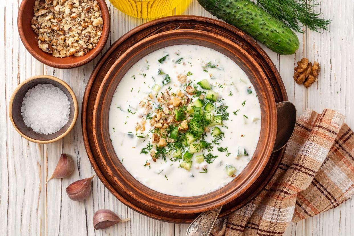 Traditional bulgarian cold summer soup tarator with yogurt, dill, cucumber and walnuts in ceramic bowl on wooden table. Top view.