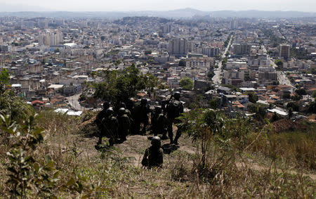 Brazilian Army soldiers take cover during an operation against drug gangs in Alemao slums complex in Rio de Janeiro, Brazil August 20, 2018. REUTERS/Ricardo Moraes