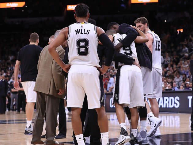 Patty Mills and the Spurs huddle around Tony Parker. (Getty Images)