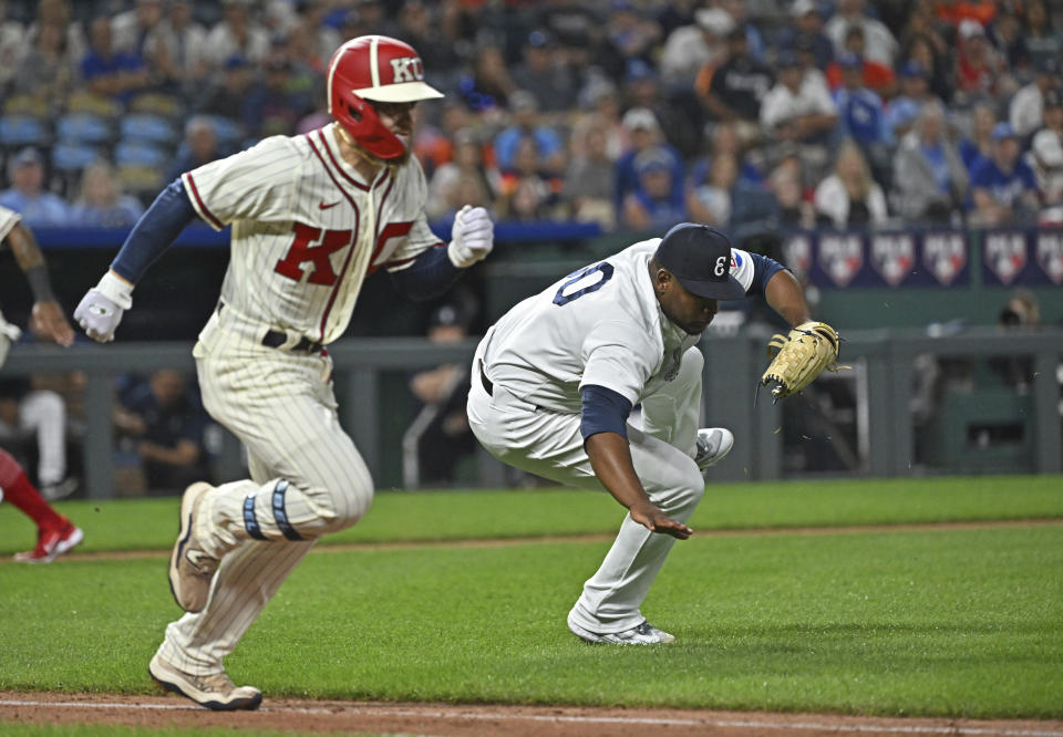 Houston Astros relief pitcher Hector Neris, right, tumbles while attempting to field the ball as Kansas City Royals Kyle Isbel, left, runs down the first base line during the seventh inning of a baseball game Saturday, Sept. 16, 2023, in Kansas City, Mo. (AP Photo/Peter Aiken)