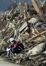 A fire fighter takes a rest before a pile of debris at Rikuzentakada city in Iwate prefecture. Japan raced to avert a meltdown of two reactors at a quake-hit nuclear plant Monday as the death toll from the disaster on the ravaged northeast coast was forecast to exceed 10,000