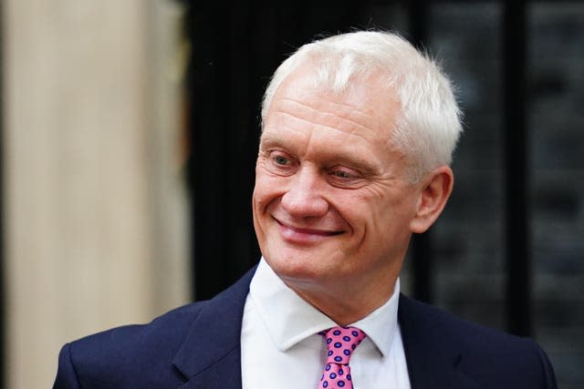 A man with white hair in a blue suit and pink tie