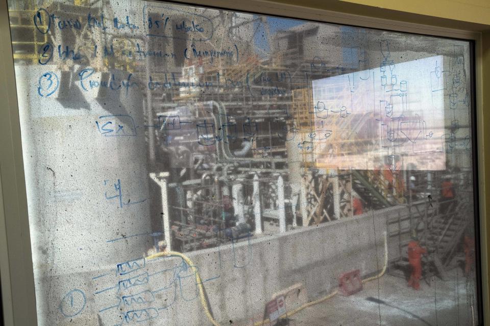 Tubes and machinery can be seen through a dirty factory window at the SQM processing plant in Antofagasta, Chile, Wednesday, April 19, 2023. (AP Photo/Rodrigo Abd)