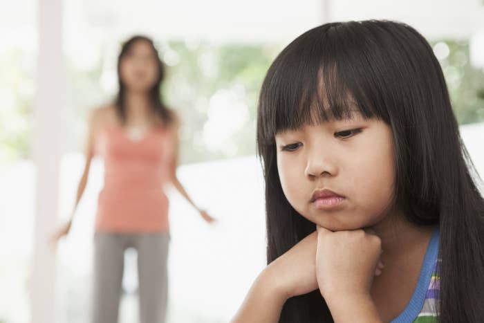 a young girl looking down with a woman behind her