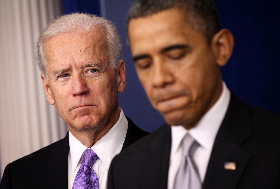 Joe Biden et Barack Obama debout, tous deux en costume d'affaires avec des expressions sérieuses