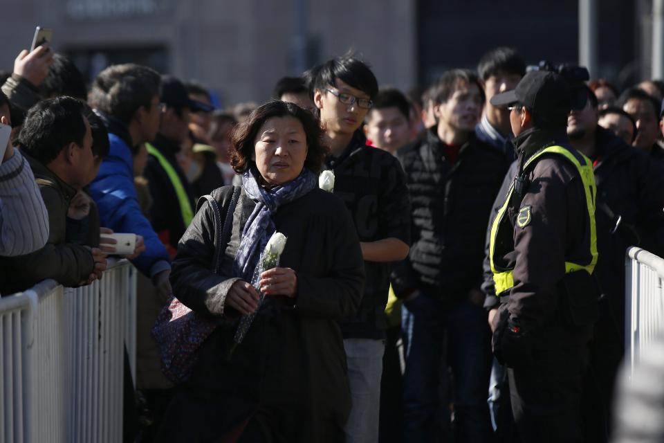 People hold flowers during a memorial ceremony in memory of people who were killed in a stampede incident during a New Year's celebration on the Bund in Shanghai