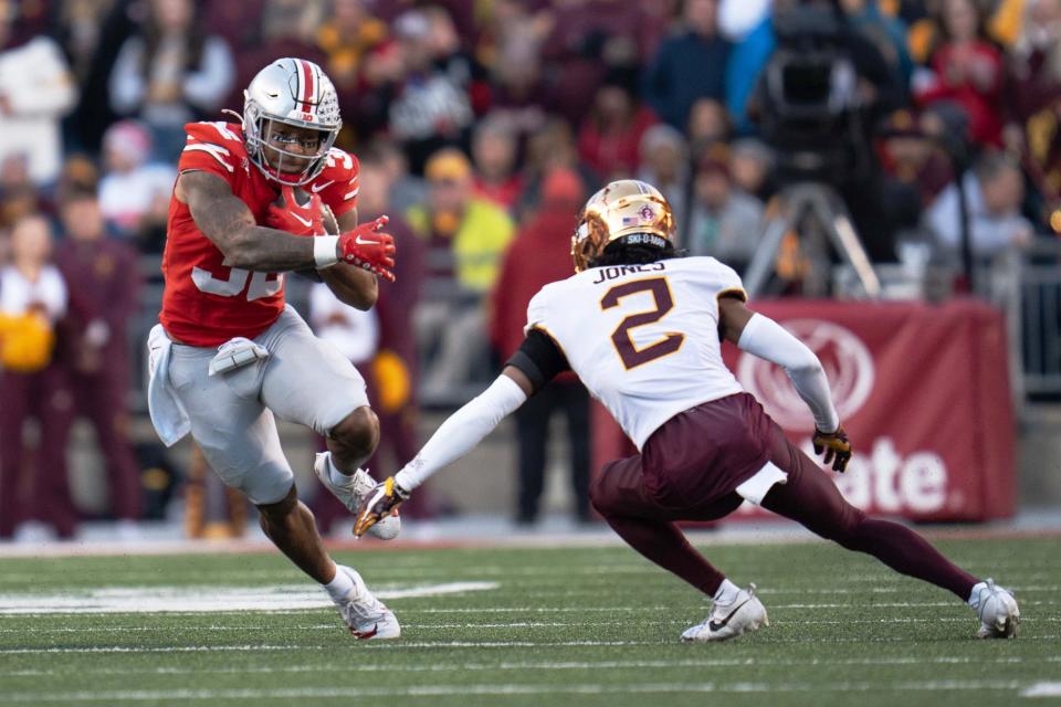 Nov 18, 2023; Columbus, Ohio, USA; 
Ohio State Buckeyes running back TreVeyon Henderson (32) runs past Minnesota Golden Gophers defensive Tre'Von Jones’ (2) tackle attempt during the first half of their game on Saturday, Nov. 18, 2023 at Ohio Stadium.