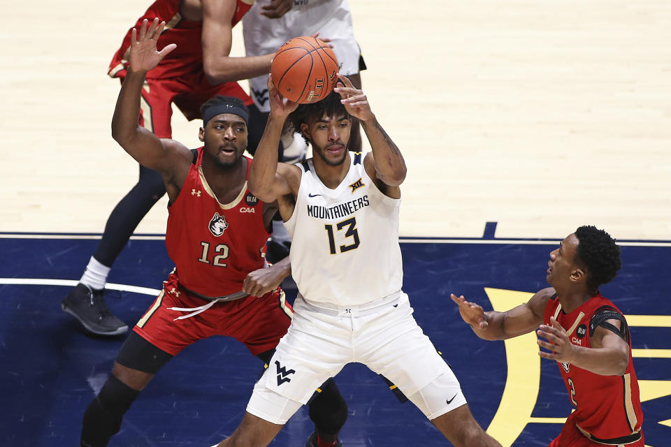 West Virginia forward Isaiah Cottrell (13) is defended by Northeastern forward Alex Nwagha (12) and guard Tyson Walker (2) during the first half of an NCAA college basketball game Tuesday, Dec. 29, 2020, in Morgantown, W.Va. (AP Photo/Kathleen Batten)