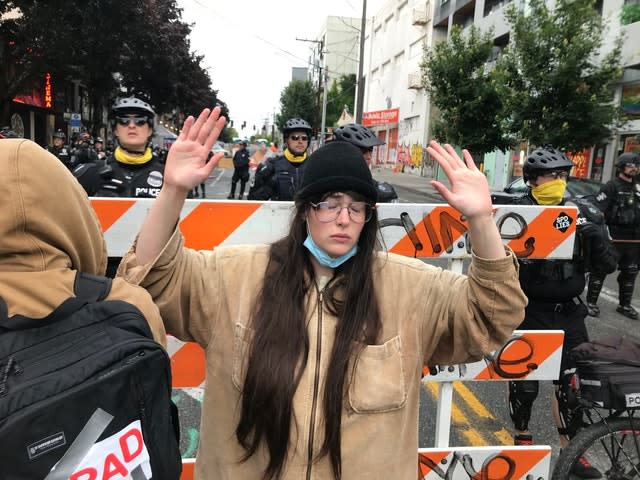 A protester stands with her hand up in front of a road blocked by Seattle police (Aron Ranen/AP)