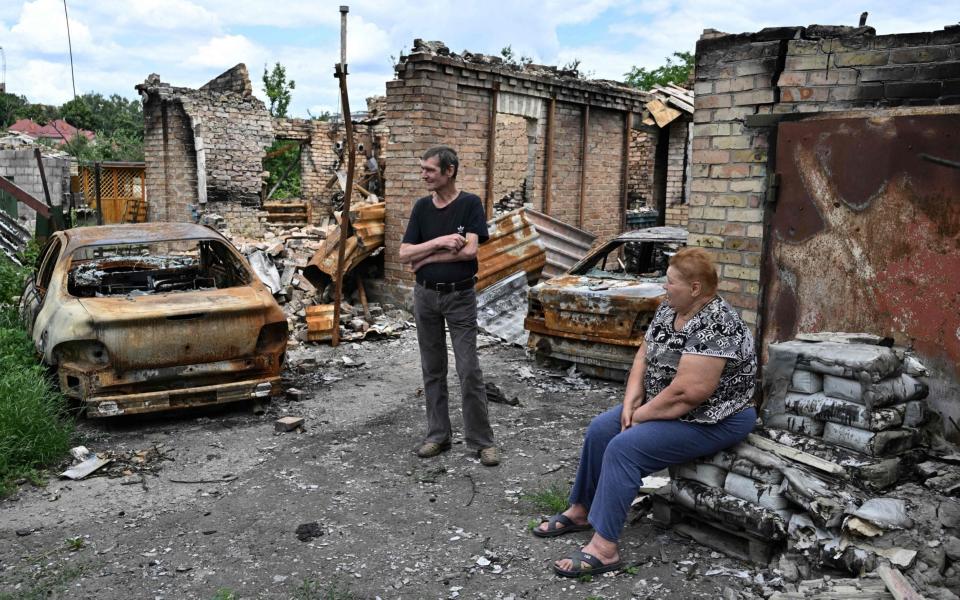 Local residents wait for humanitarian aid next to destroyed houses along a street in the town of Bucha, northwest of the Ukrainian capital of Kyiv - AFP