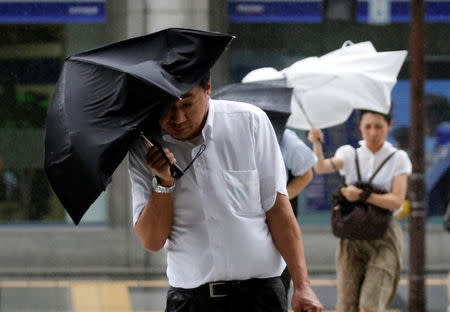 Passersby using an umbrella struggle against a heavy rain and wind as Typhoon Shanshan approaches Japan's mainland in Tokyo, Japan August 8, 2018. REUTERS/Toru Hanai