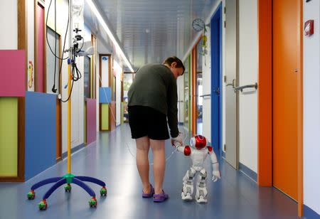 Belgian Ian Frejean, 11, walks with "Zora" the robot, a humanoid robot designed to entertain patients and to support care providers, at AZ Damiaan hospital in Ostend, Belgium June 16, 2016. REUTERS/Francois Lenoir