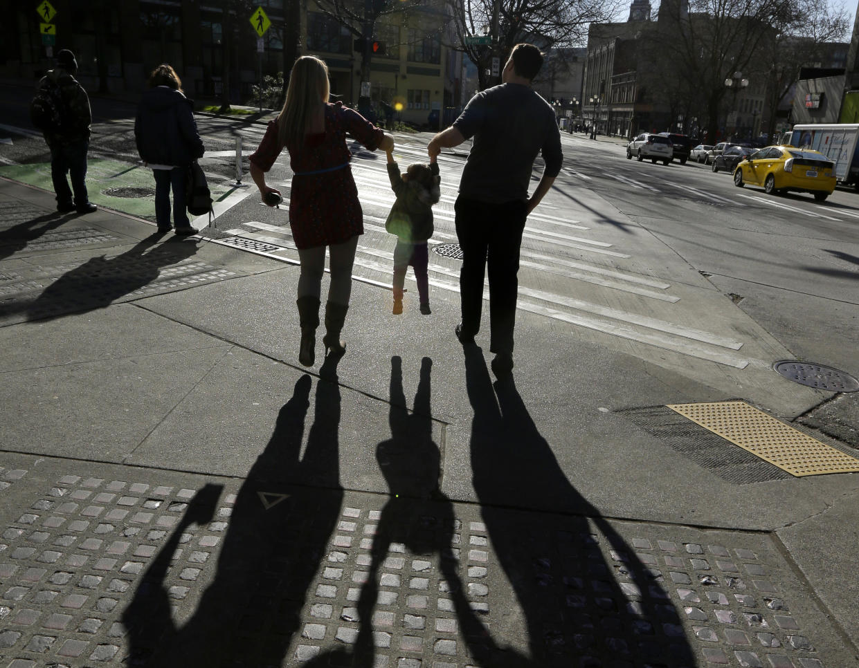 FILE - In this March 3, 2015, file photo, a child is lifted by her parents at a street corner in downtown Seattle. The expansion of a child tax credit helped seal Congress’ approval of the Republican tax overhaul. (AP Photo/Ted S. Warren, File)